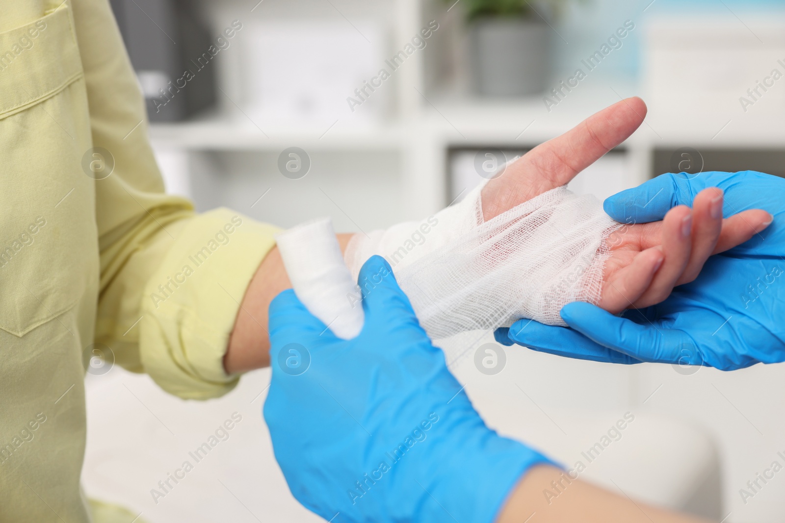 Photo of Doctor bandaging patient's burned hand indoors, closeup