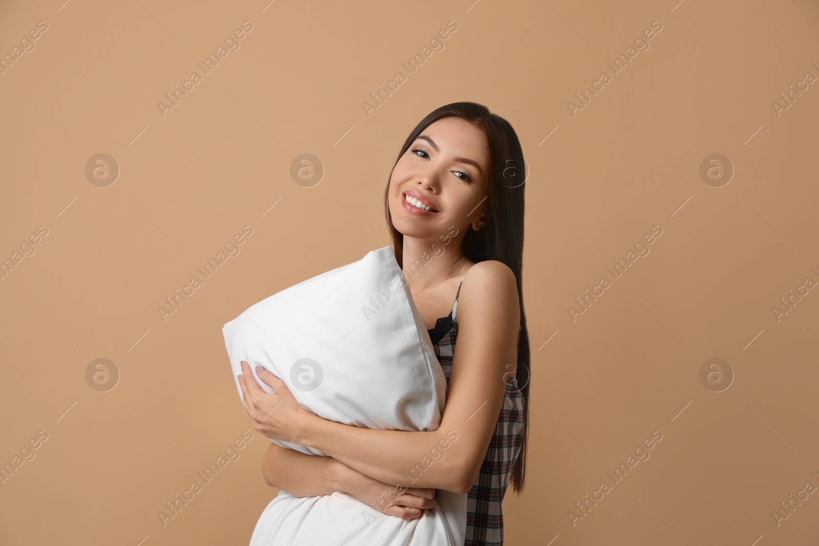 Photo of Beautiful Asian woman with pillow on beige background. Bedtime