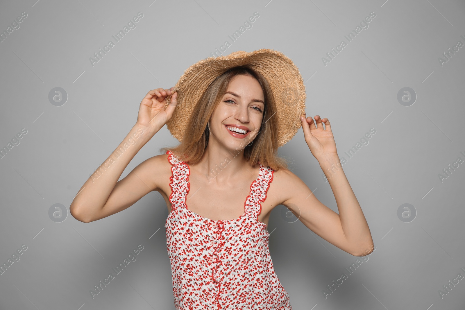 Photo of Beautiful young woman wearing straw hat on light grey background. Stylish headdress