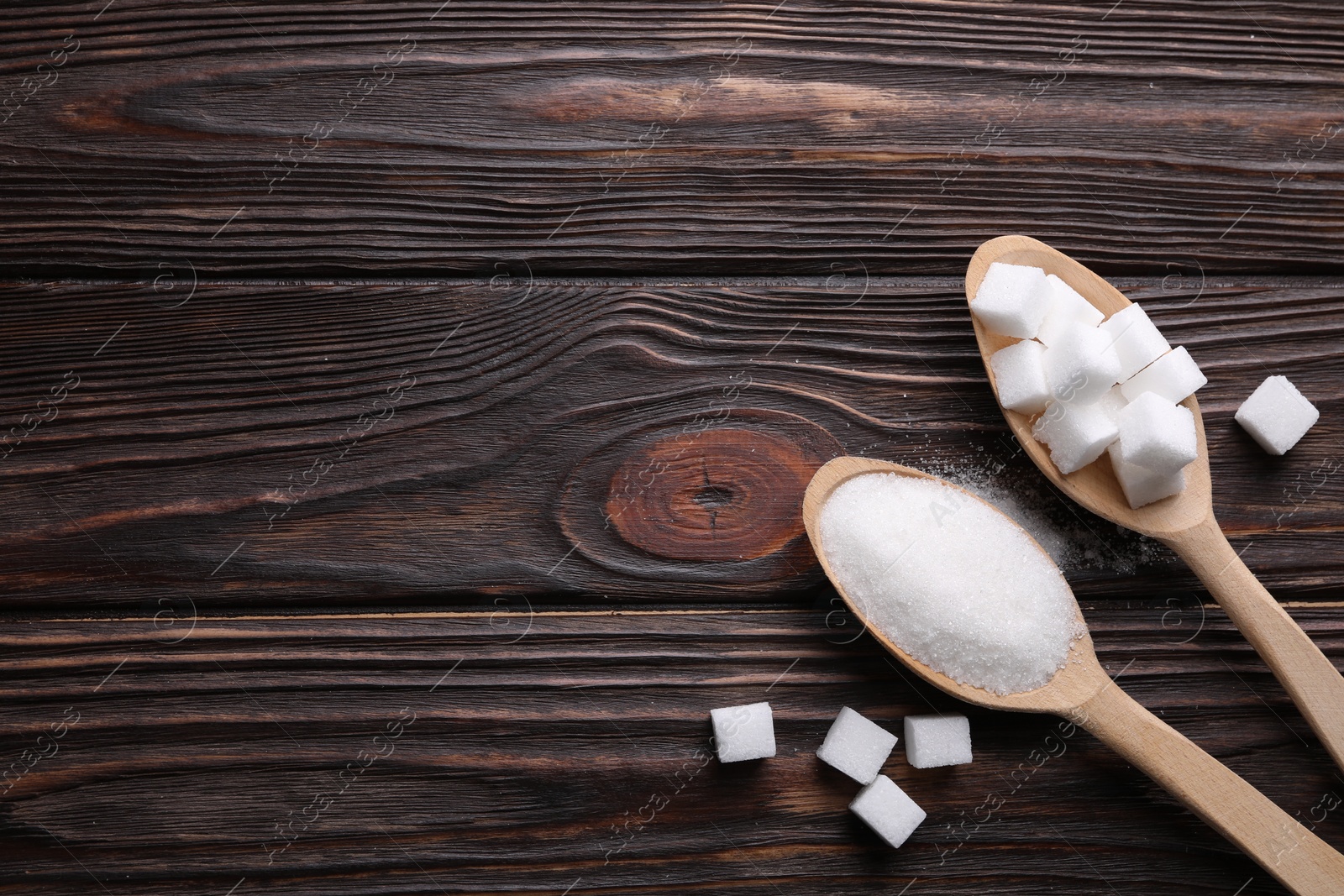 Photo of Spoons with different types of white sugar on wooden table, flat lay. Space for text