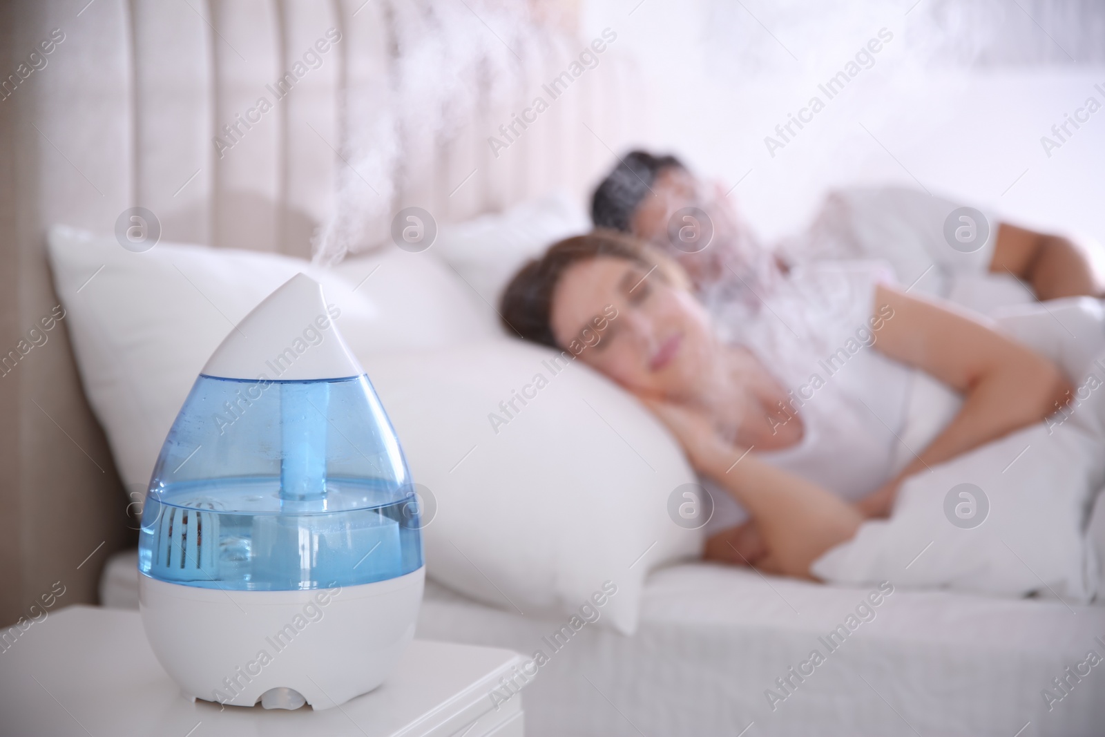 Photo of Couple sleeping in bedroom with modern air humidifier