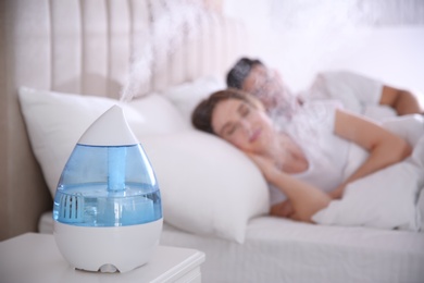 Photo of Couple sleeping in bedroom with modern air humidifier