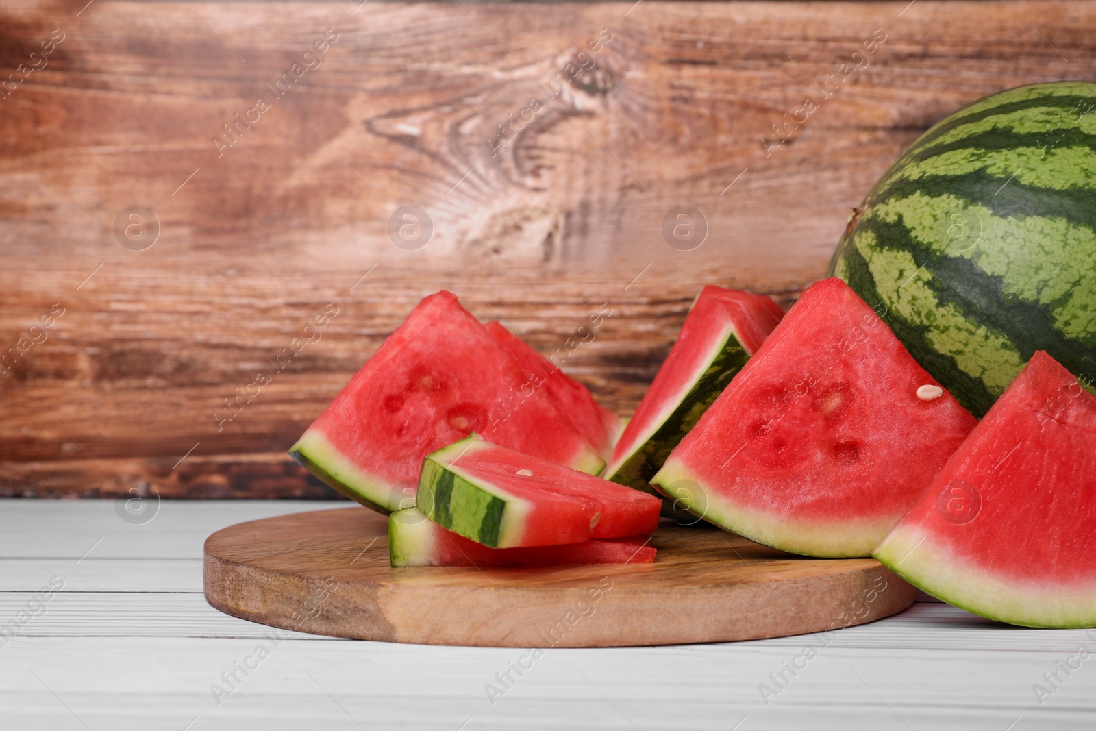 Photo of Juicy ripe cut and whole watermelons on white wooden table