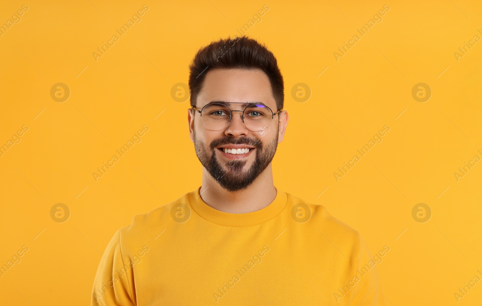 Photo of Handsome man wearing glasses on orange background