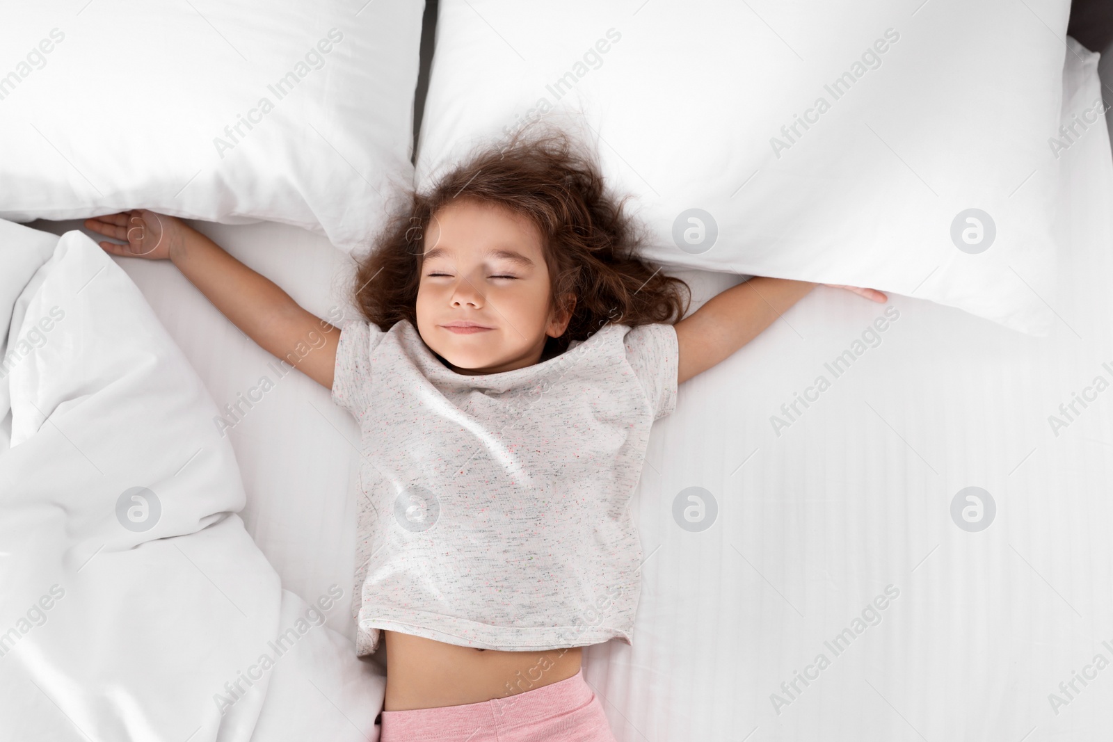 Photo of Cute little girl sleeping on cozy bed, view from above