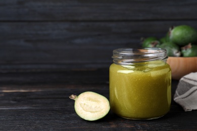 Feijoa jam and fresh fruit on black wooden table. Space for text