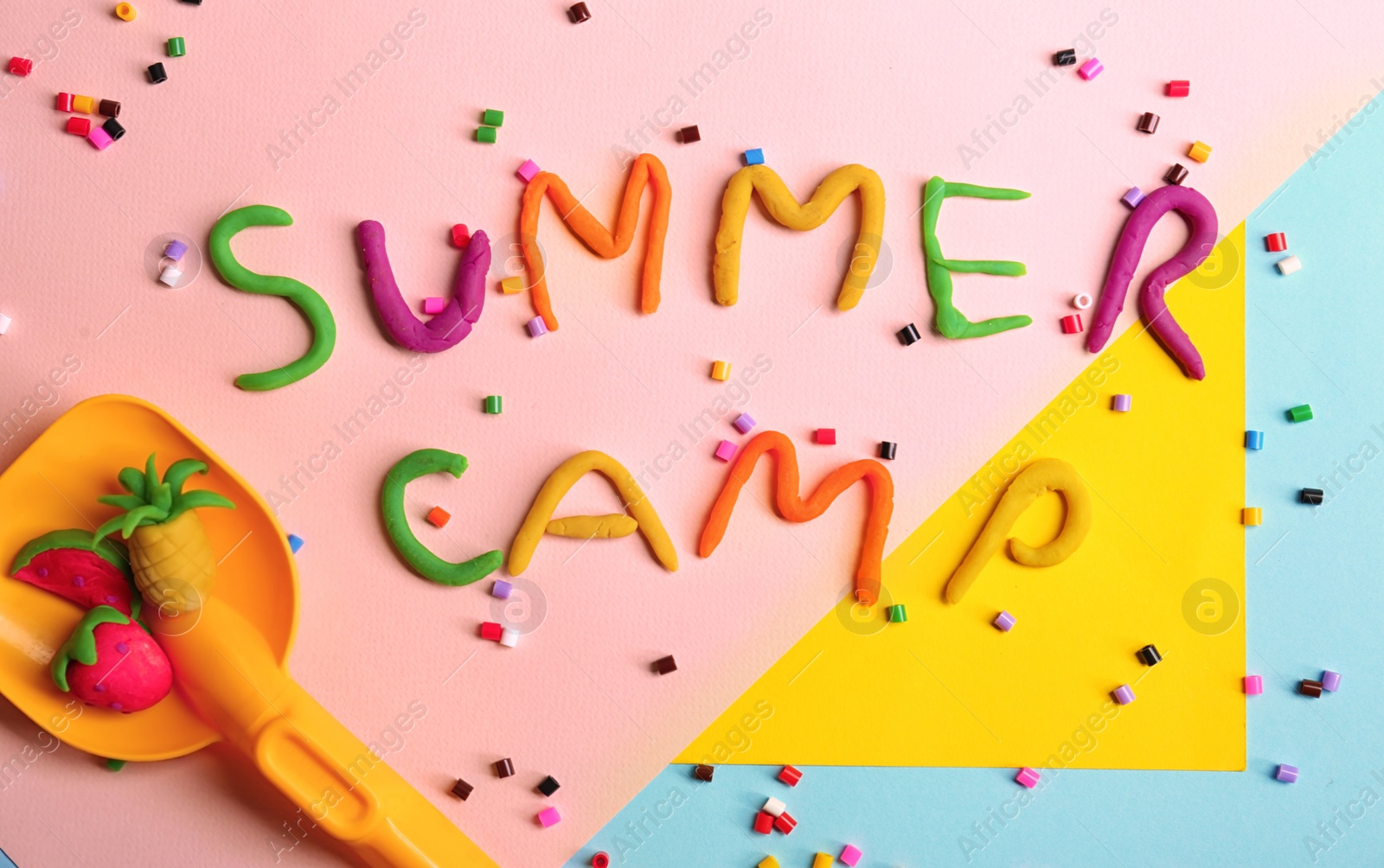Photo of Flat lay composition with words SUMMER CAMP made from modelling clay, beads and plastic shovel on color background