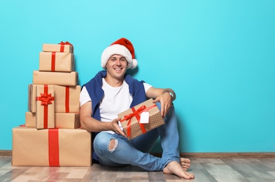 Photo of Young man with Christmas gifts near color wall