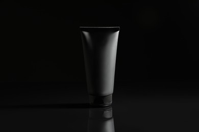 Tube of men's facial cream on black background
