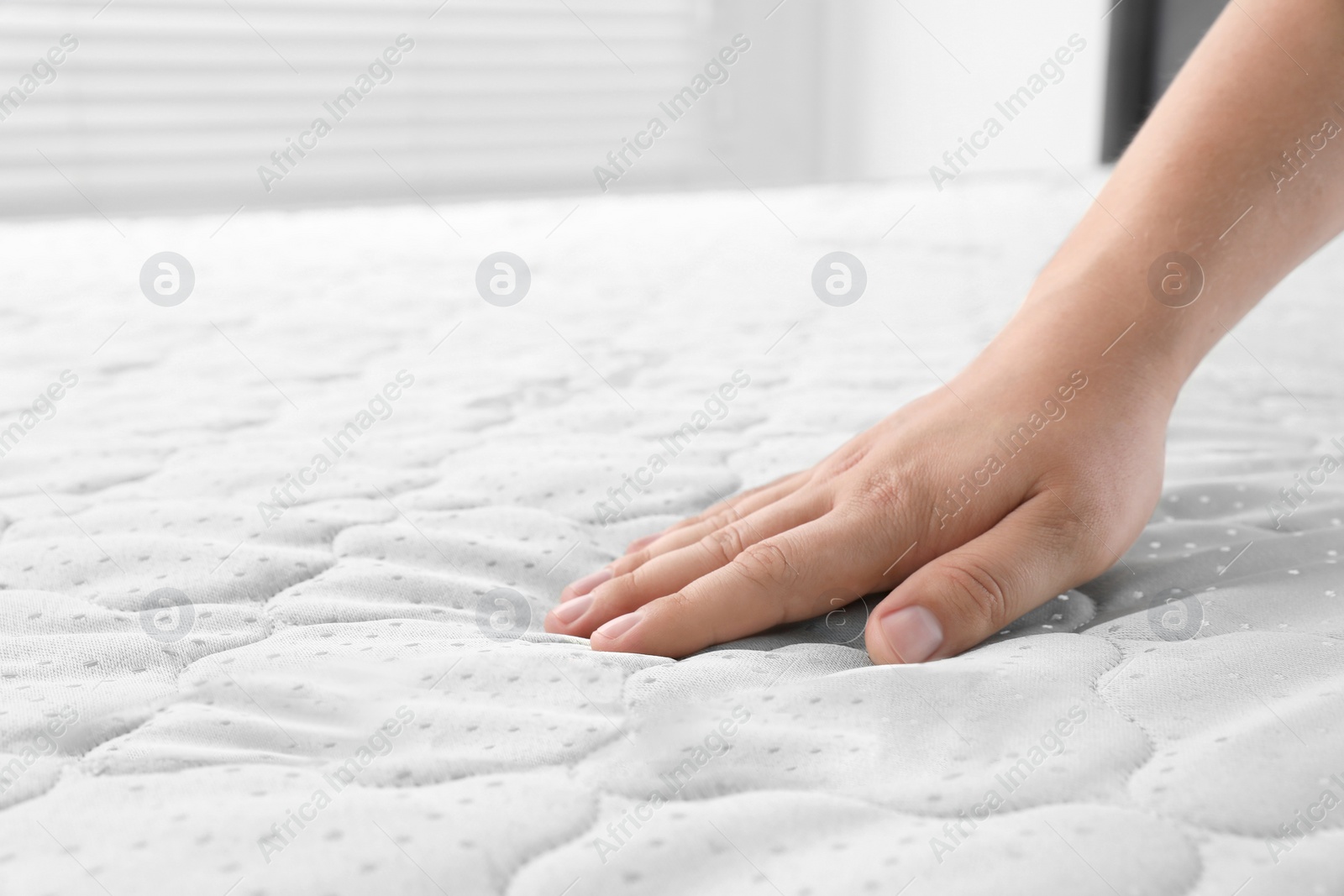 Photo of Woman touching soft light green mattress, closeup. Space for text