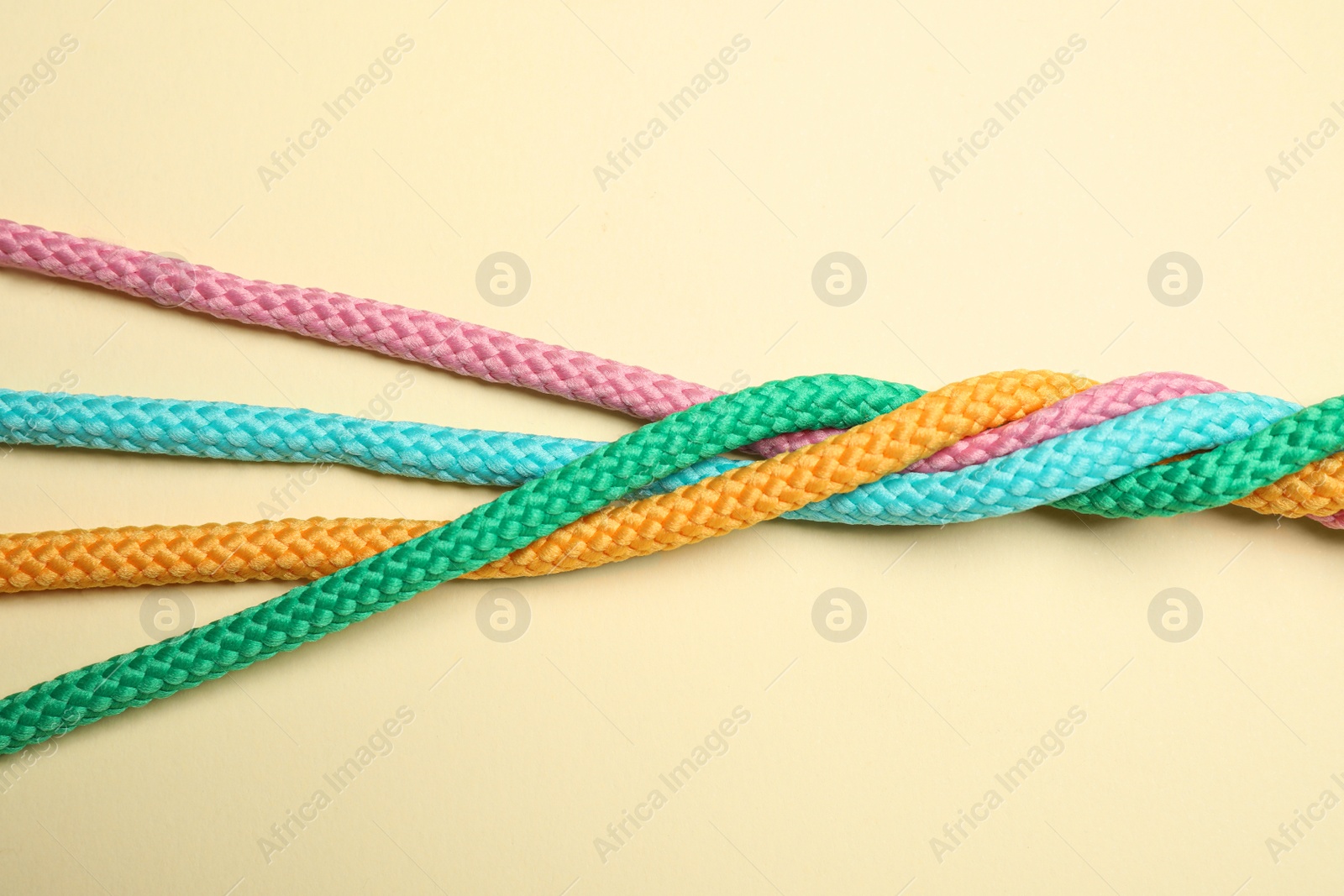 Photo of Twisted colorful ropes on beige background, top view. Unity concept