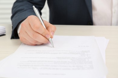 Photo of Man signing document at wooden table, closeup