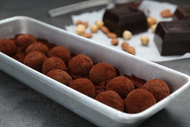 Delicious chocolate candies powdered with cocoa on grey table, closeup
