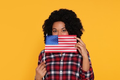 Photo of 4th of July - Independence Day of USA. Woman with American flag on yellow background