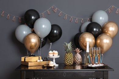 Photo of Party treats and items on table in room decorated with balloons