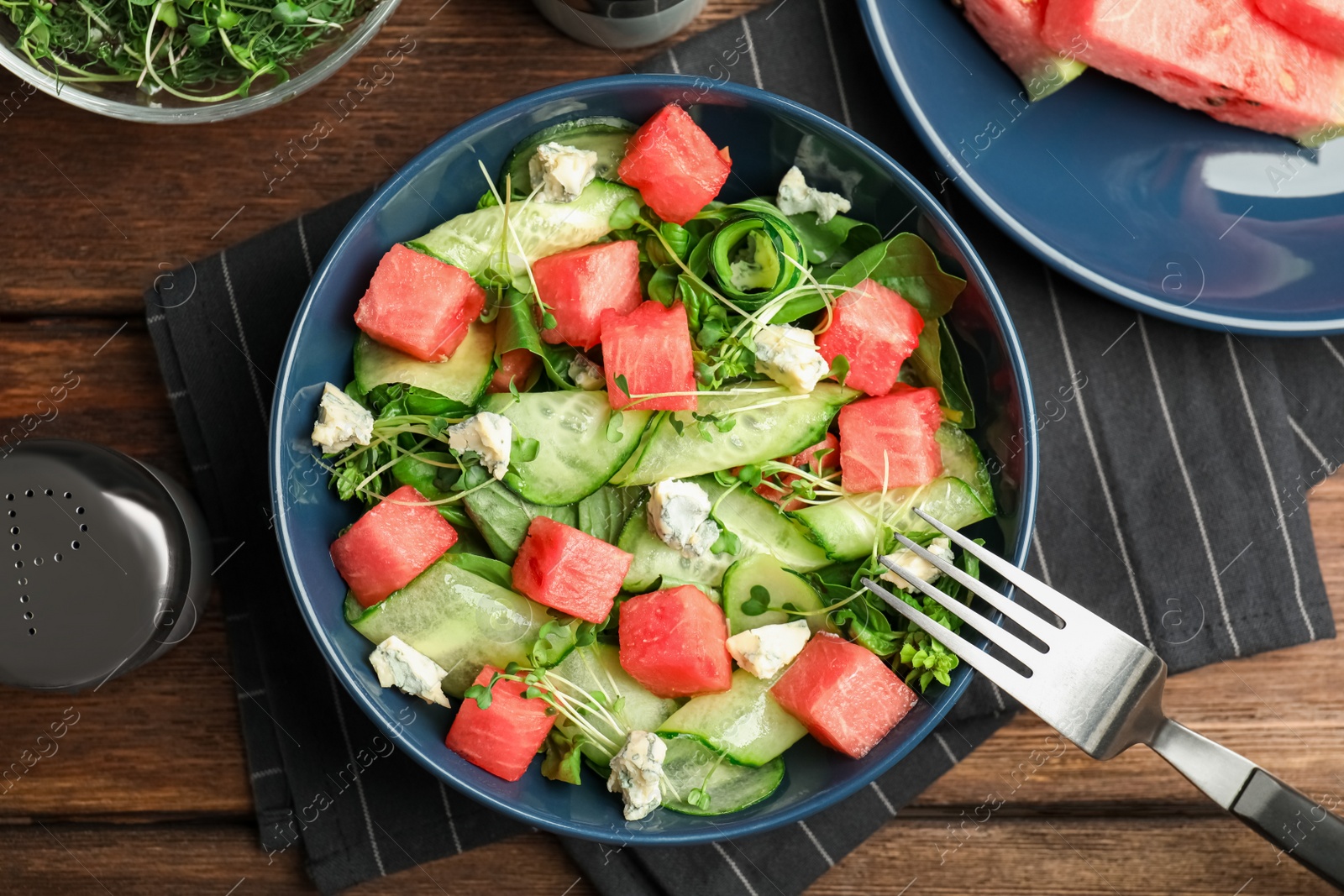 Photo of Delicious salad with watermelon served on wooden table, flat lay