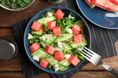 Photo of Delicious salad with watermelon served on wooden table, flat lay