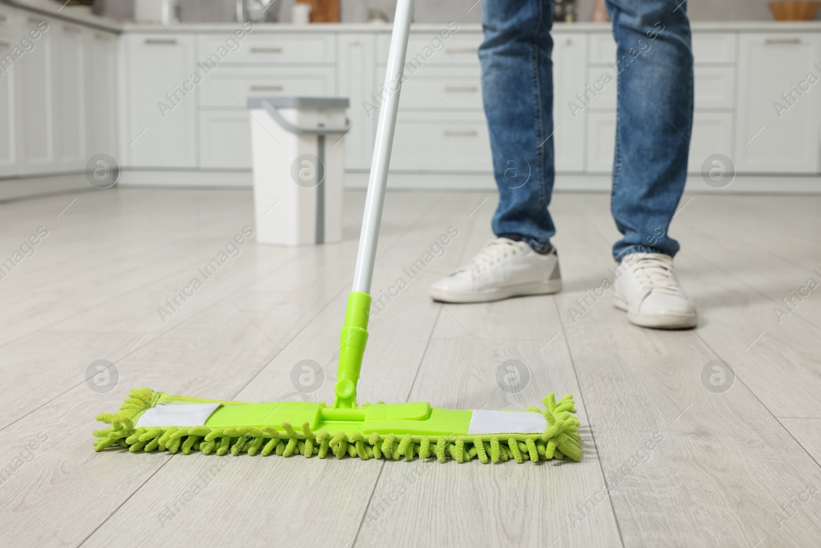 Photo of Man cleaning floor with mop indoors, closeup