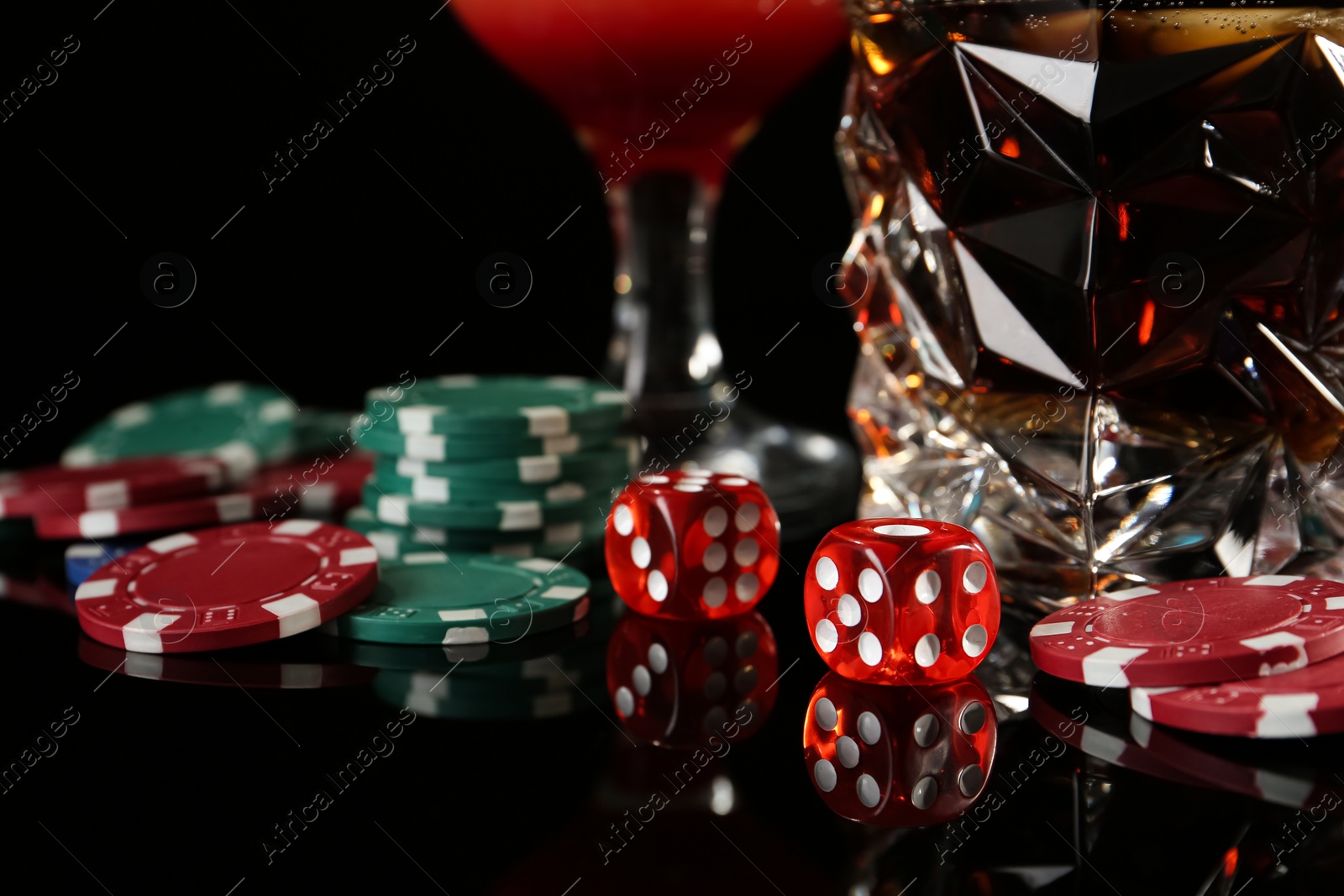 Photo of Casino chips, dice and alcohol drinks on dark background, closeup