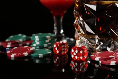 Photo of Casino chips, dice and alcohol drinks on dark background, closeup