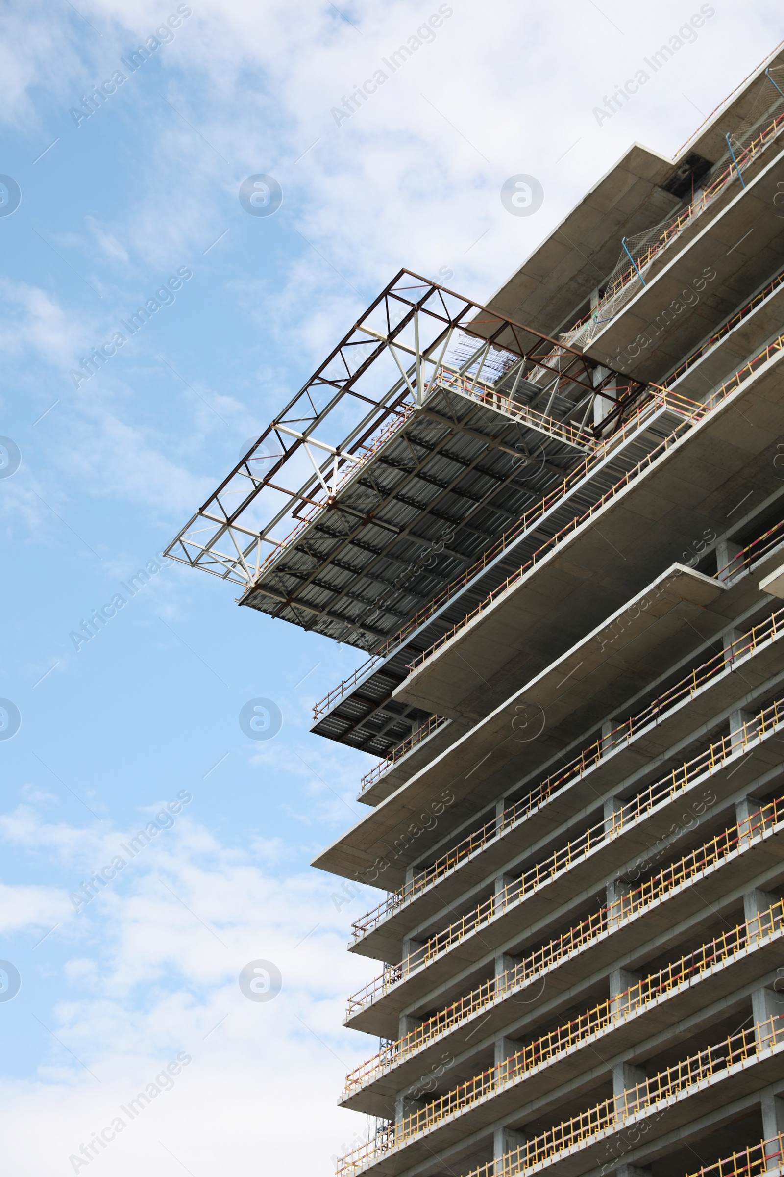 Photo of Multistory building under construction against cloudy sky, low angle view