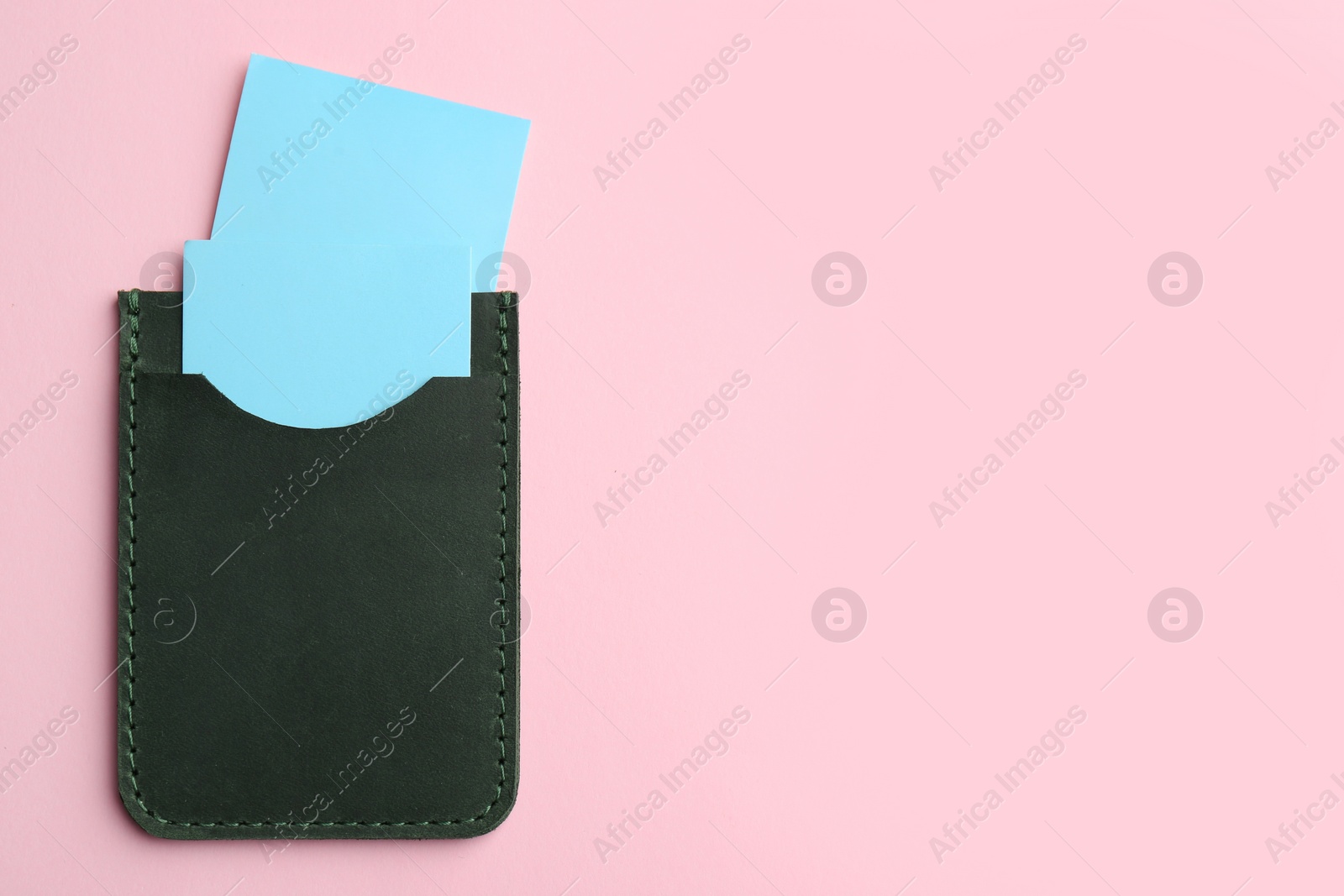 Photo of Leather business card holder with blank cards on pink background, top view. Space for text