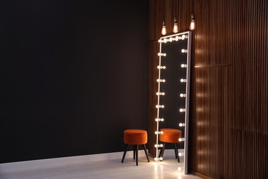 Full length dressing mirror with lamps and stool in stylish room interior. Space for text
