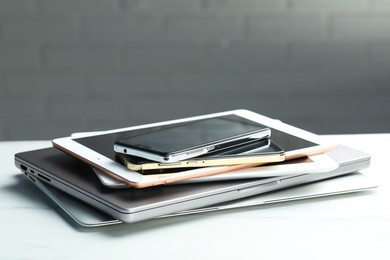 Photo of Stack of electronic devices on white table, closeup. Space for text