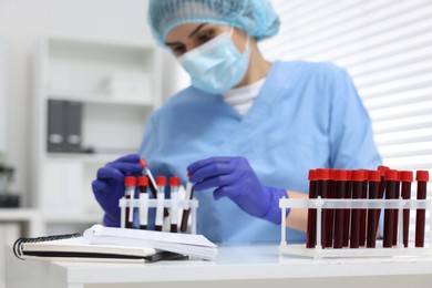 Laboratory testing. Doctor with blood samples in tubes at white table indoors, selective focus