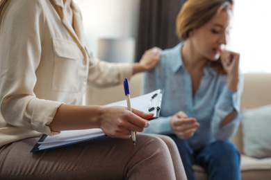 Photo of Professional psychotherapist and patient in office, focus on hands with clipboard