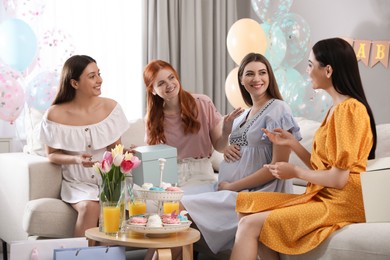 Happy pregnant woman spending time with friends at baby shower party