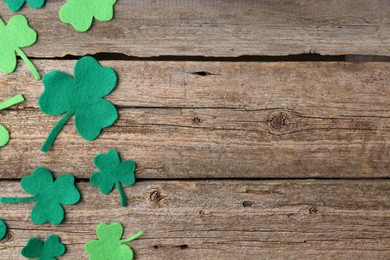 Photo of St. Patrick's day. Decorative clover leaves on wooden background, flat lay. Space for text