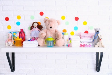 Baby accessories on shelf near white brick wall