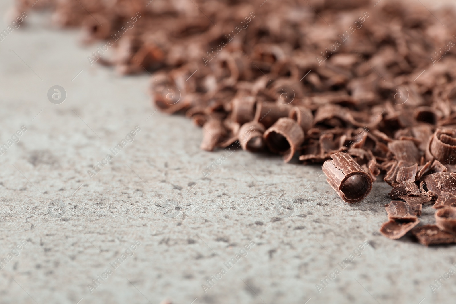 Photo of Curls of tasty chocolate on gray background, closeup with space for text