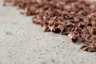 Photo of Curls of tasty chocolate on gray background, closeup with space for text