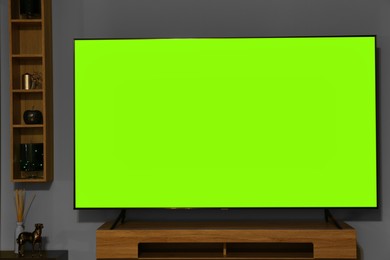 Photo of Modern plasma TV on wooden table and wall shelves with different decor in living room