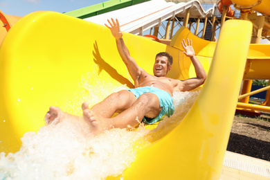 Man on slide at water park. Summer vacation