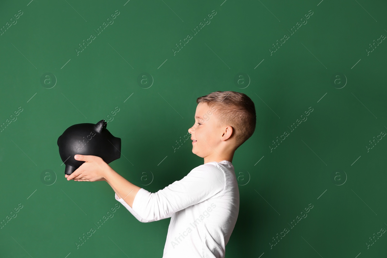 Photo of Little boy with piggy bank on color background