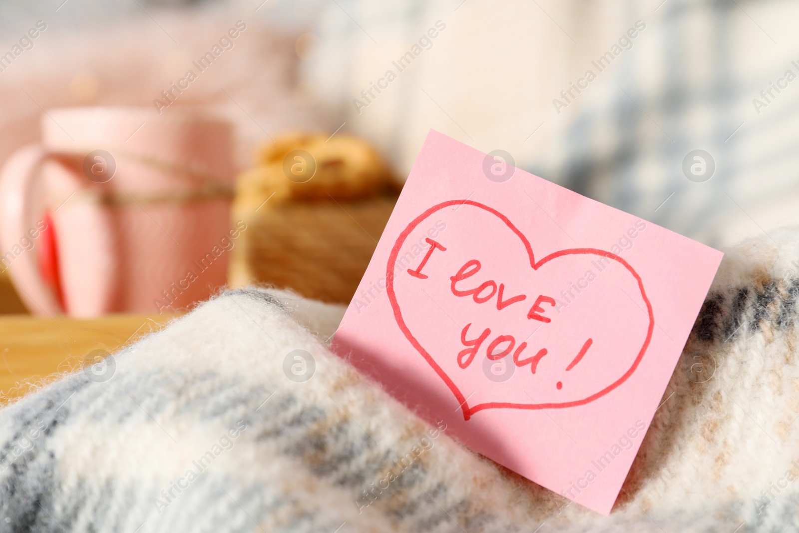 Photo of Note with phrase I Love You on warm plaid