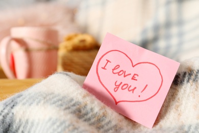 Photo of Note with phrase I Love You on warm plaid