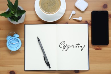 Image of Open notebook with word Copywriting and pen on wooden table, flat lay. Workplace with cup of coffee