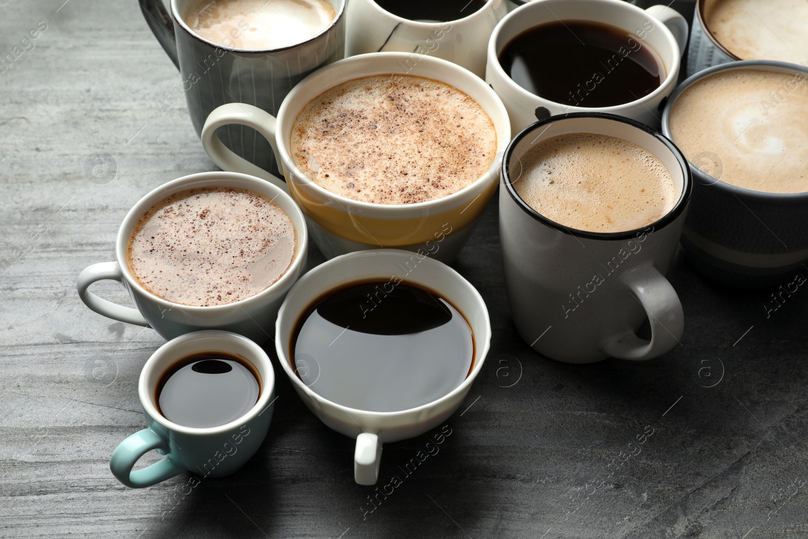 Photo of Many cups of different coffees on slate table