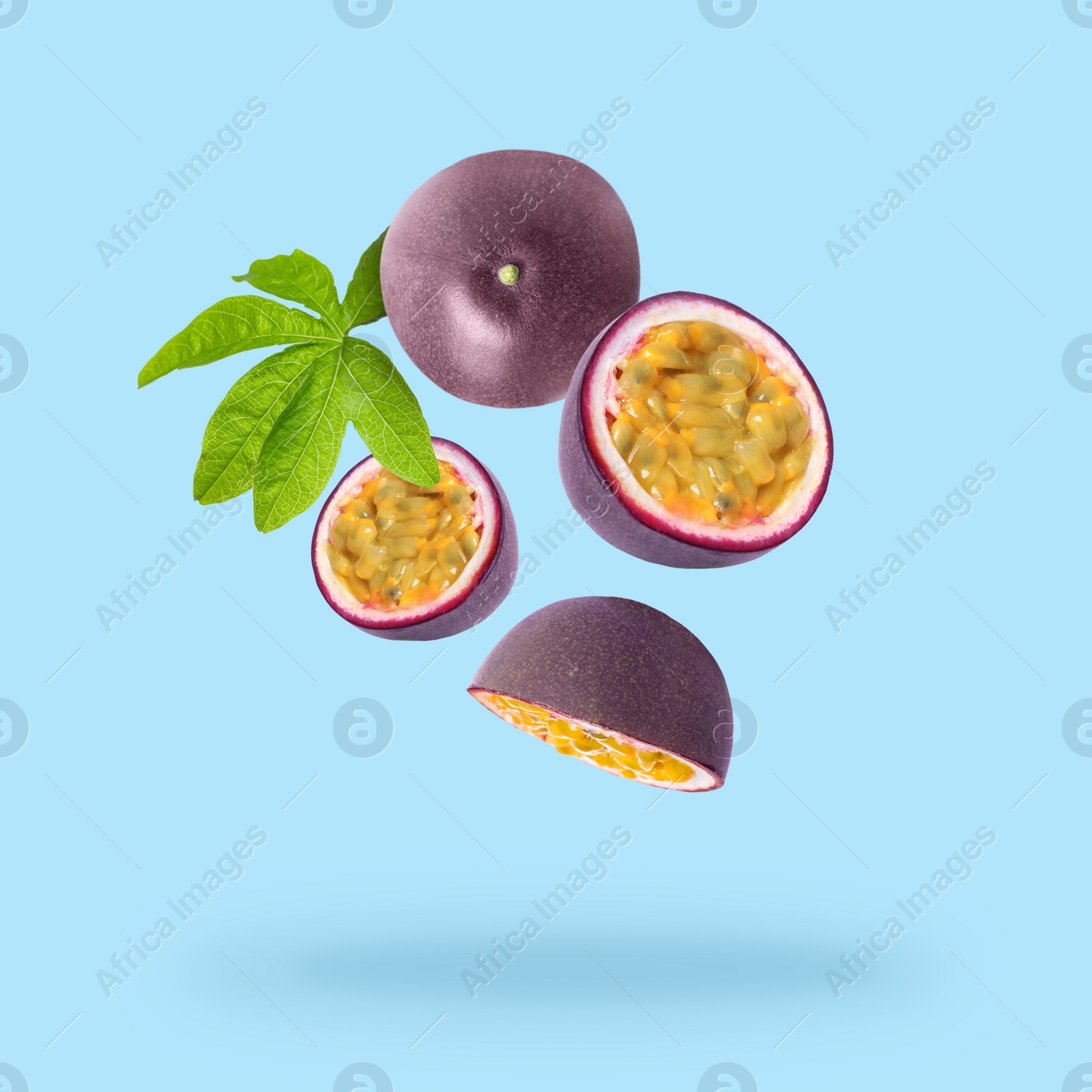 Image of Tasty passion fruits and passiflora leaf falling on light blue background