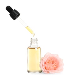 Photo of Dripping rose essential oil from pipette into bottle and flower isolated on white