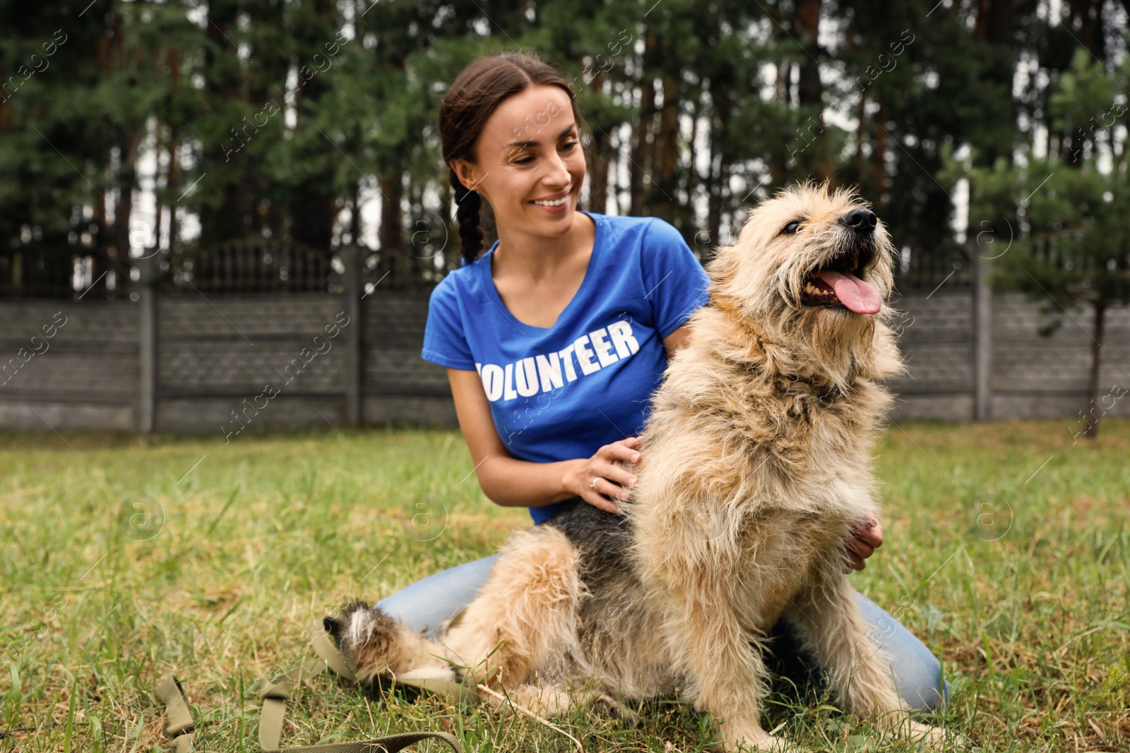 Photo of Female volunteer with homeless dog at animal shelter outdoors