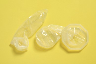 Photo of Unrolled female and male condoms on yellow background. Safe sex