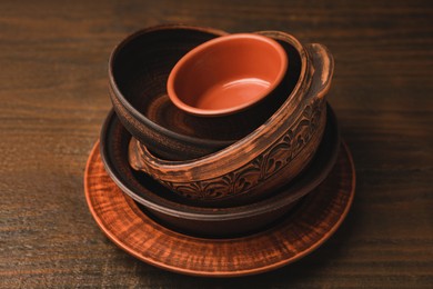 Photo of Set of clay dishes on wooden table. Cooking utensils