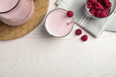 Photo of Tasty fresh milk shake and raspberries on white table, flat lay. Space for text