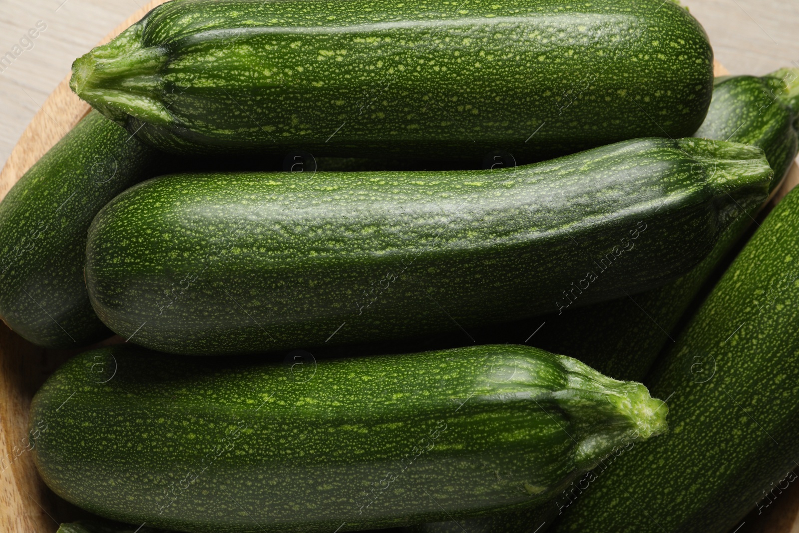 Photo of Many raw ripe zucchinis in bowl, closeup