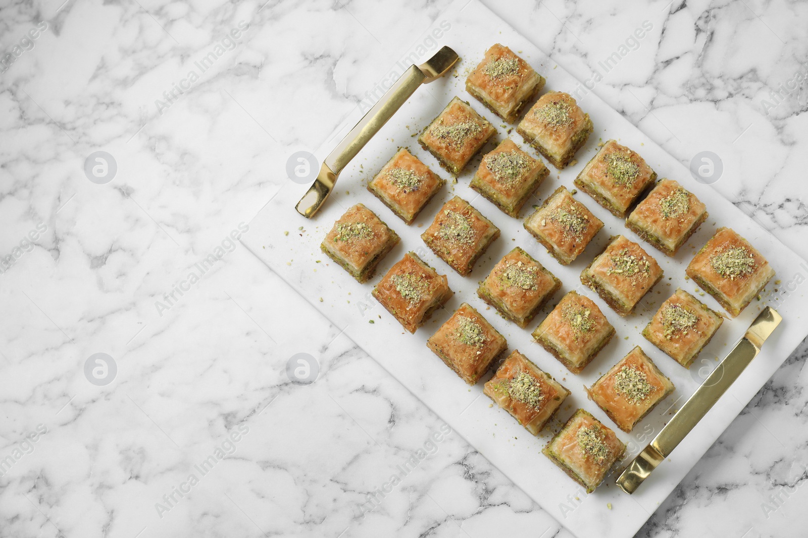 Photo of Delicious fresh baklava with chopped nuts on white marble table, top view and space for text. Eastern sweets